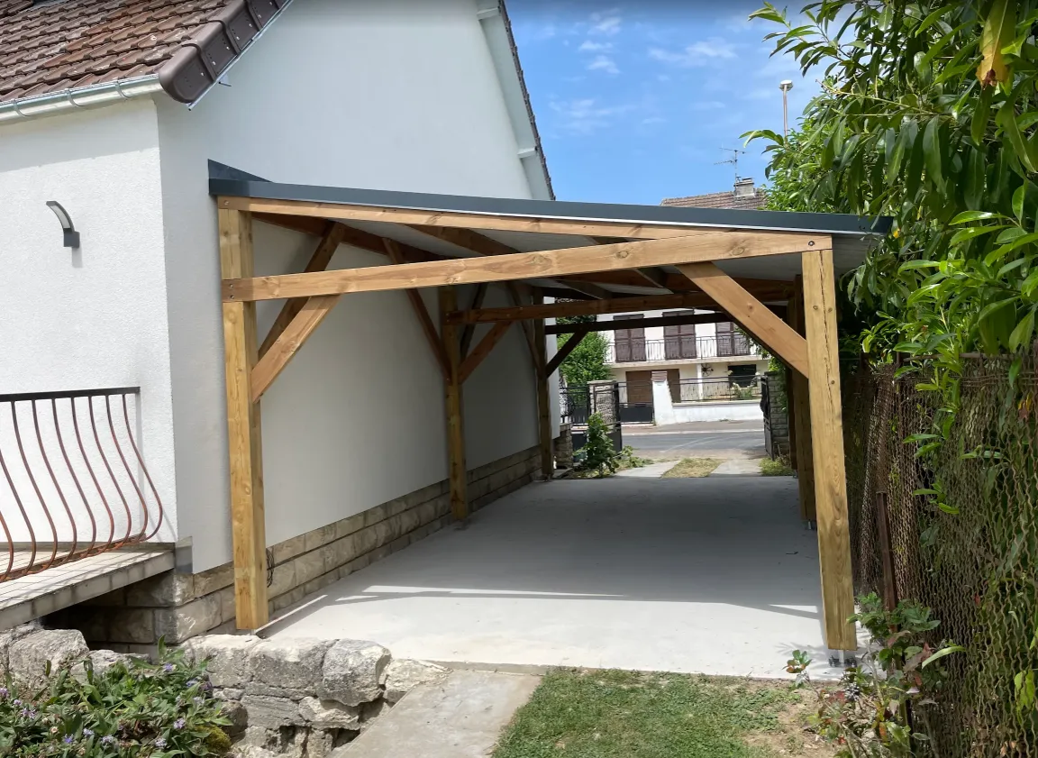 Carport bois autoporté avec toiture en bac acier, vu depuis le jardin, réalisé à Crépy-en-Valois dans l'Oise