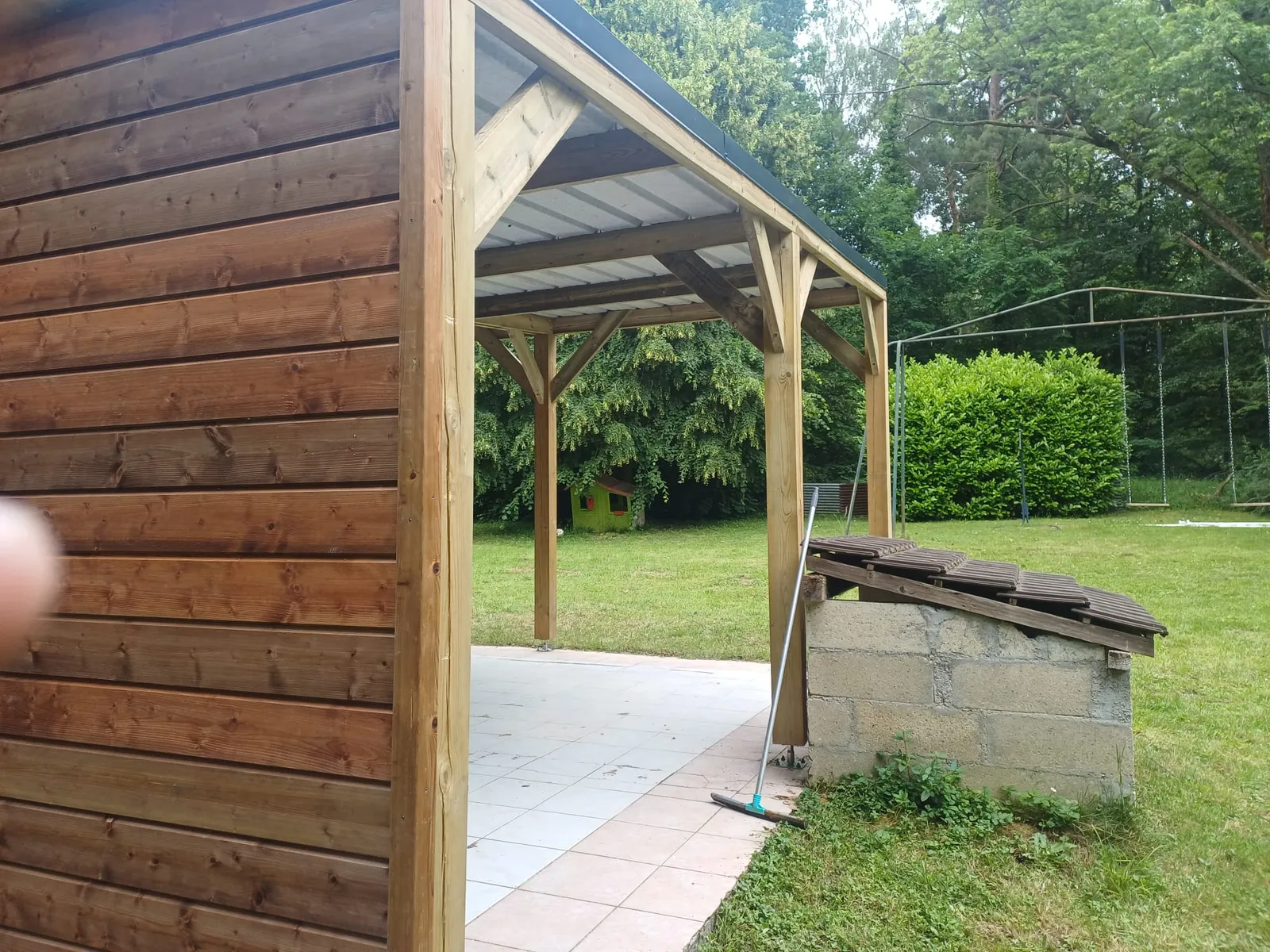 Détail de l'angle du bardage bois d'un carport ouvert sur le jardin, dans l'Aisne