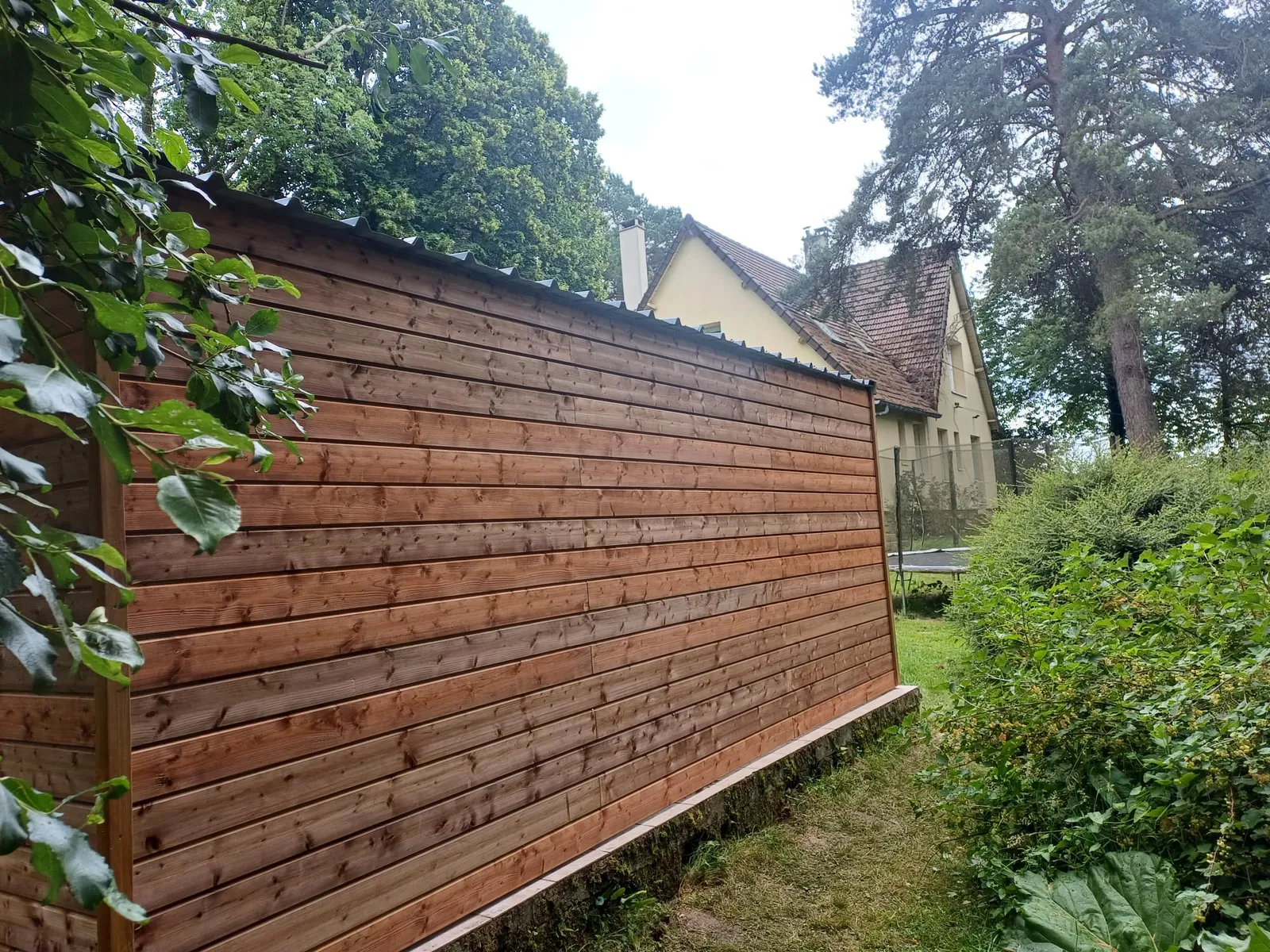 Mur en bardage bois horizontal lasuré d'un carport, vue de côté dans l'Aisne