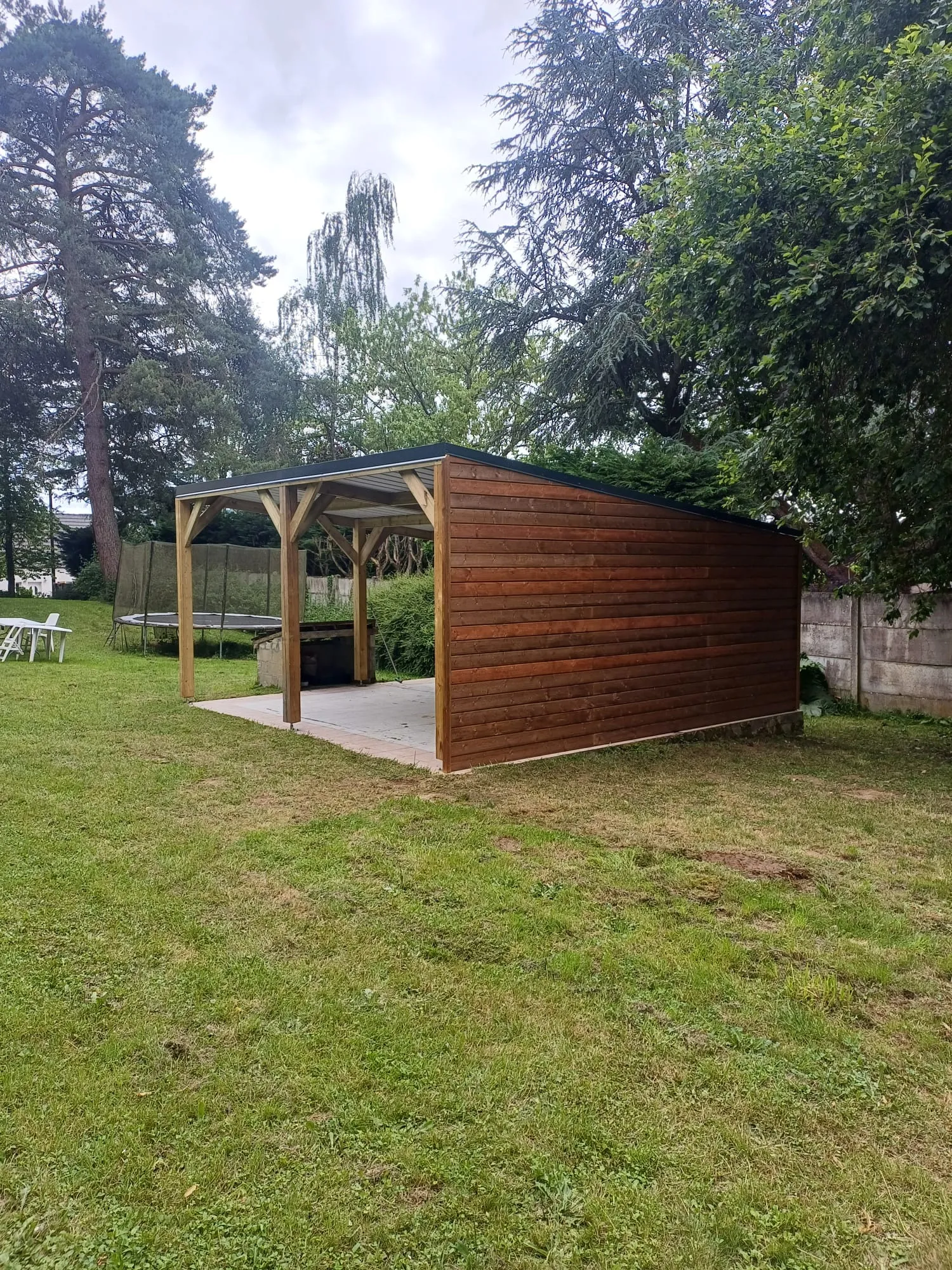 Carport bois ouvert avec dalle carrelée, intégré dans un grand jardin arboré dans l'Aisne
