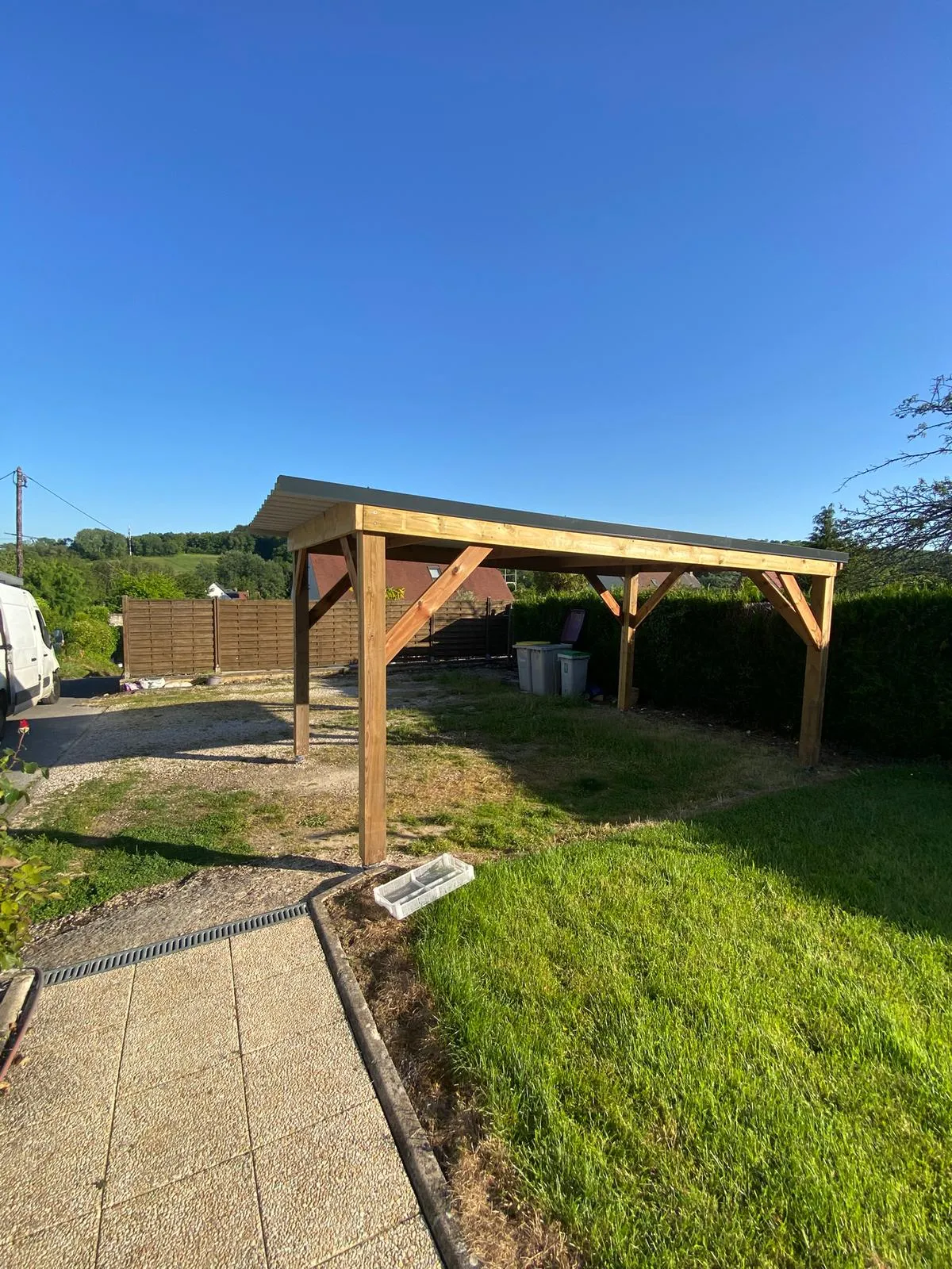 Carport bois mono-pente avec toiture bac acier réalisé dans un jardin, dans l'Aisne
