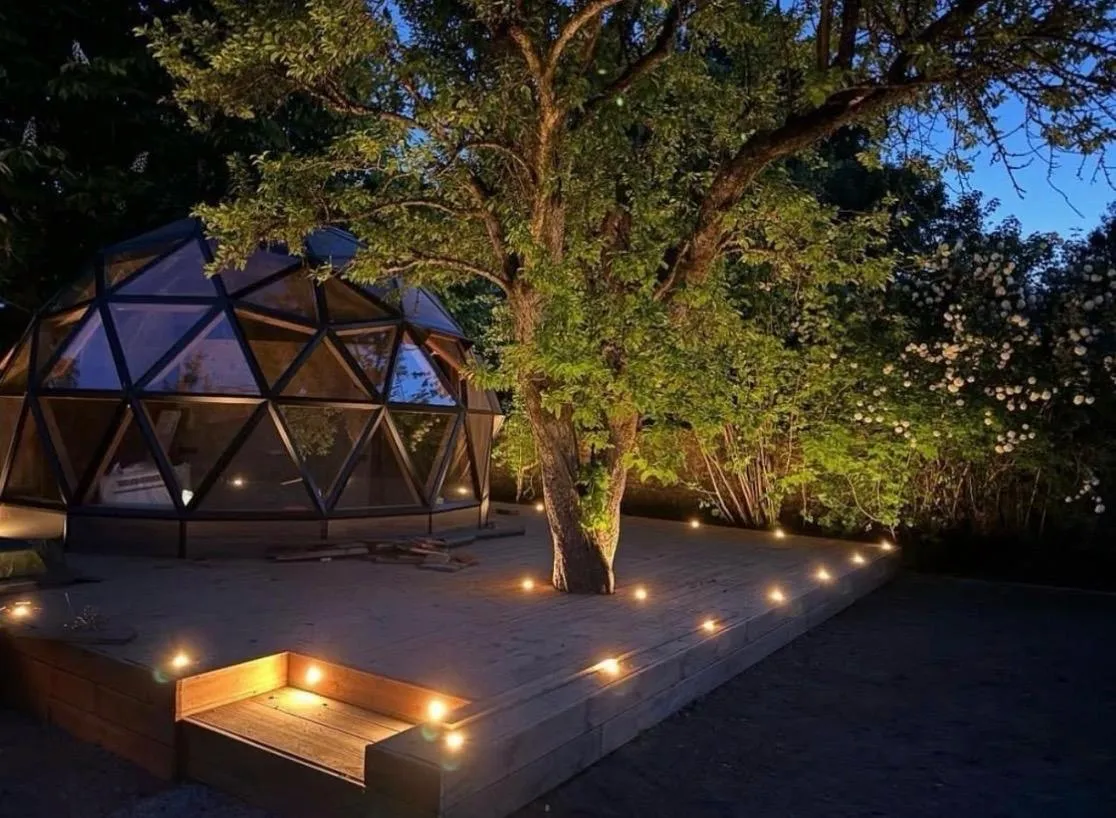 Dôme bois et terrasse éclairés à la tombée de la nuit