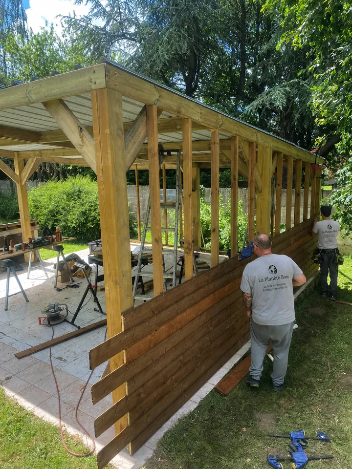 L'équipe de La Planète Bois en tee-shirt de la marque sur un chantier de carport bois