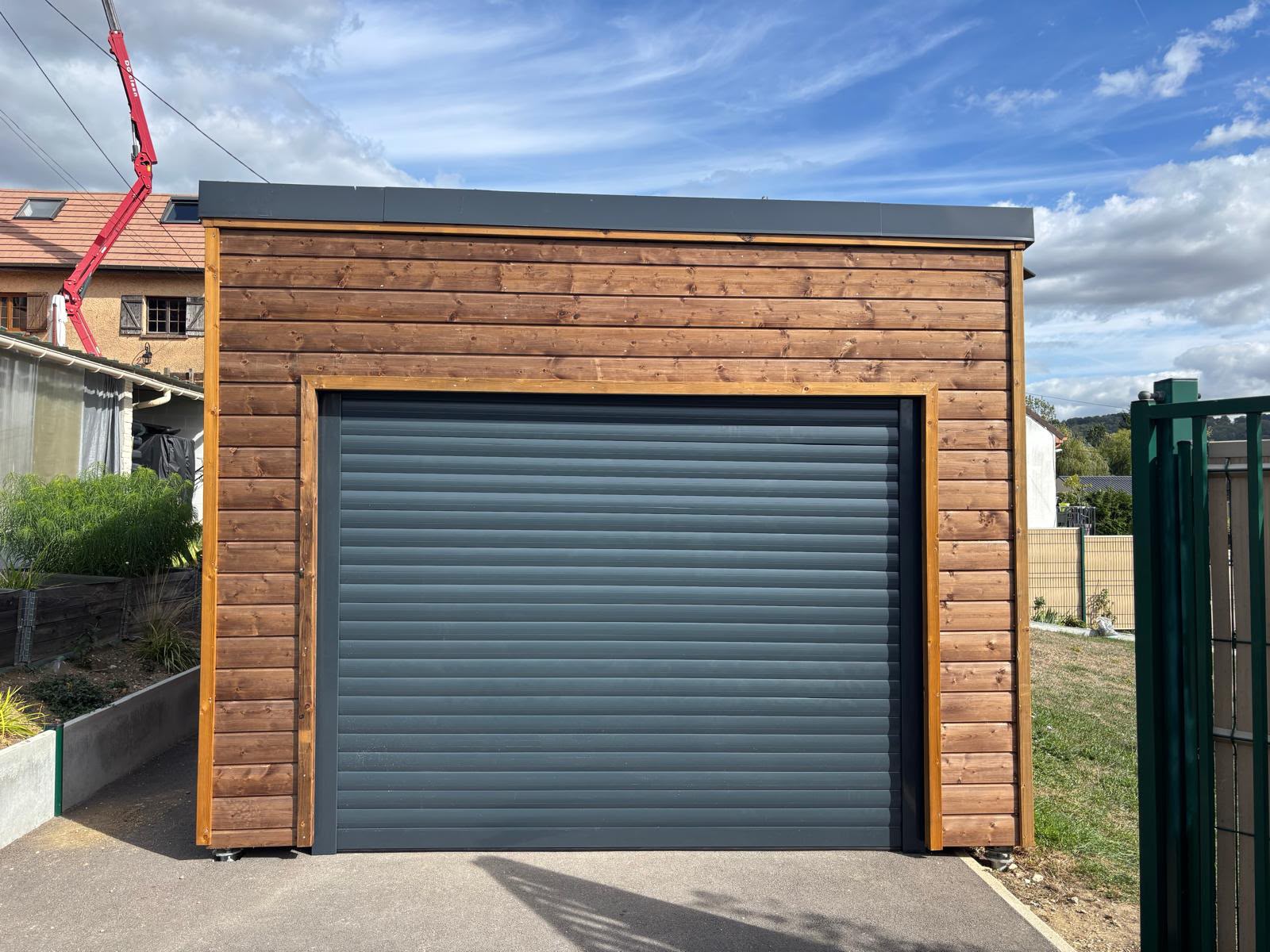 Garage en bardage bois avec porte de garage enroulable anthracite fermée, vu de face