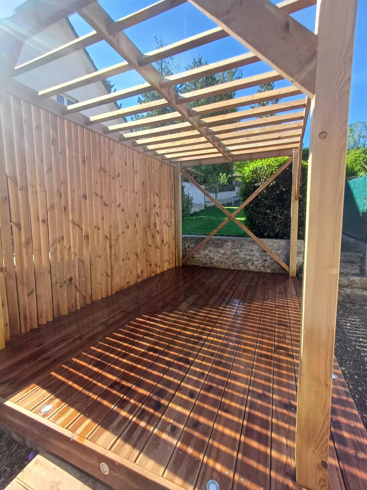 Pergola bois sur terrasse en bois avec chevrons apparents, brise-vue plein et contreventement, réalisée dans l'Aisne