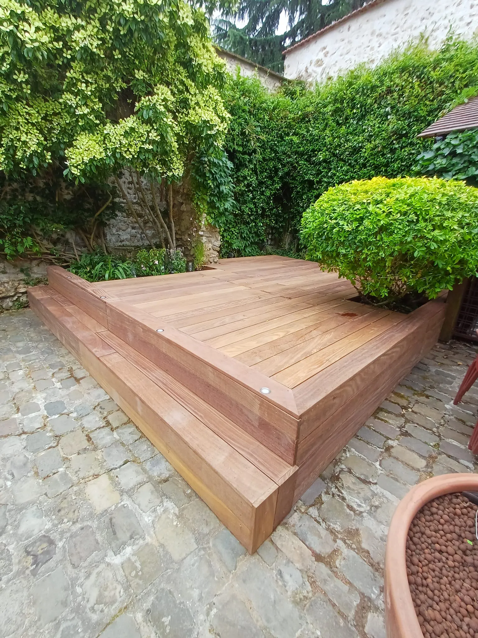 Terrasse surélevée en bois exotique cumaru avec marche depuis une cour pavée, à Chambourcy