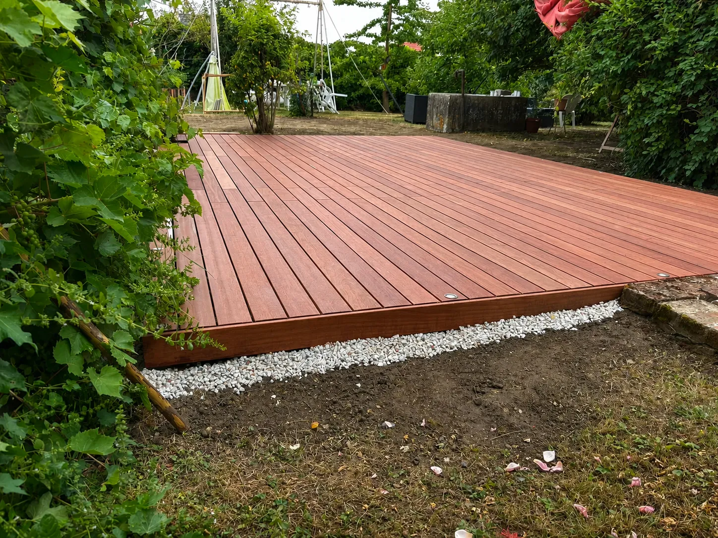 Bordure de gravier blanc drainant le long d'une terrasse en bois exotique, dans un jardin à Hermonville dans la Marne