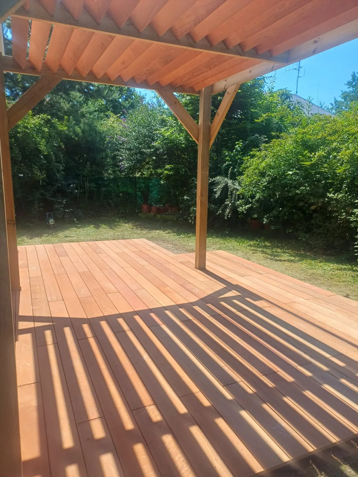 Terrasse cumaru à Bezannes avec l'ombre des lames de la pergola projetée sur le platelage, réalisée par La Planète Bois