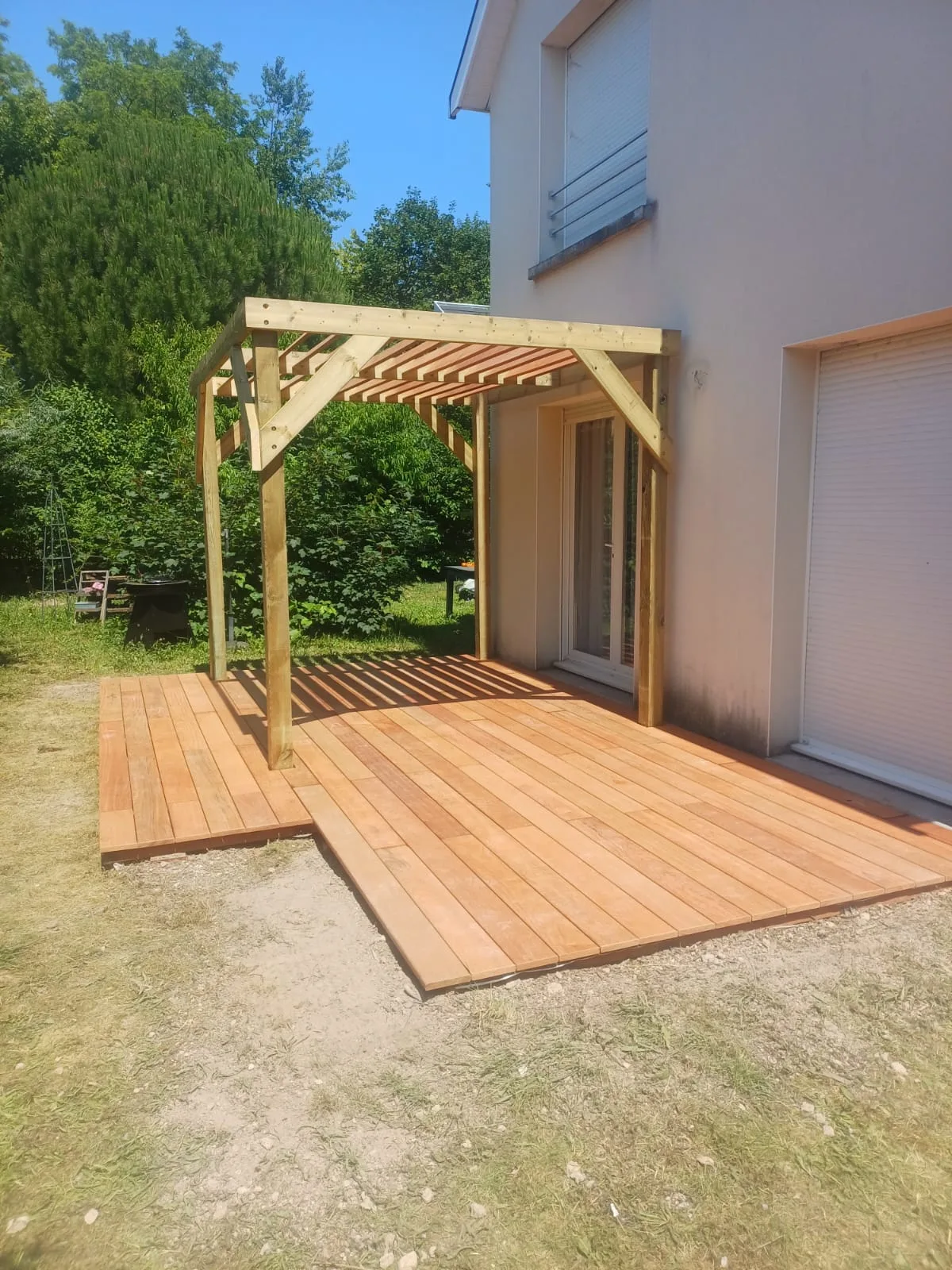 Grande terrasse en bois exotique le long de la maison avec pergola bois adossée, réalisée par La Planète Bois